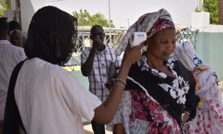 Une membre du personnel soignant prend la température d'une dame à l'hôpital de Kaolack