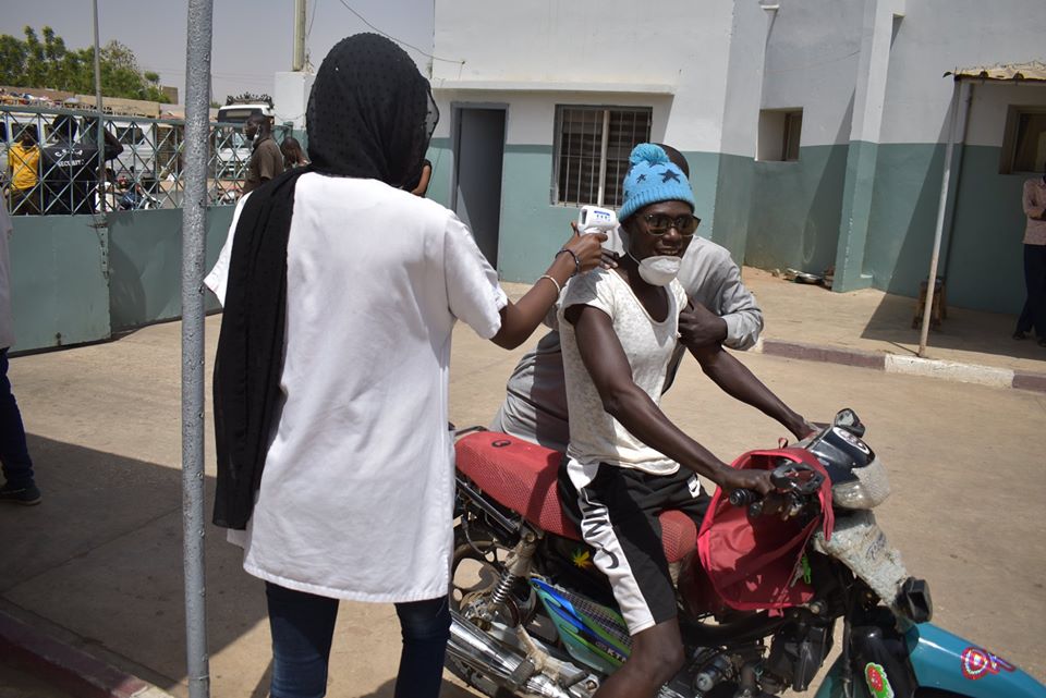 un agent de santé prend la température des visiteurs à l'hopital