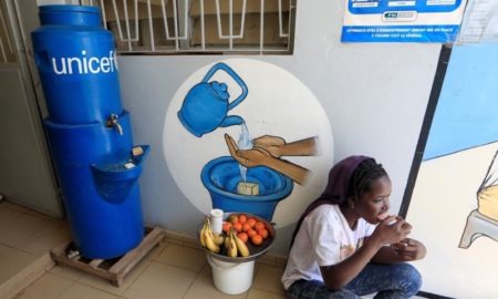 Une fille mange assise à côté d'un poste de lavage des mains contre le coronavirus