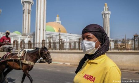 Une dame devant la mosquée à Dakar avec un masque