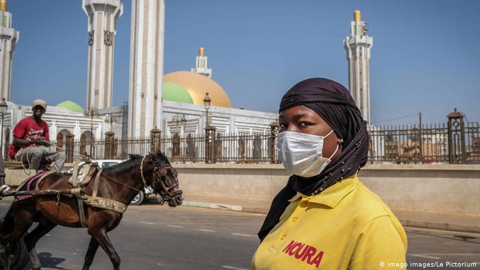 Une dame devant la mosquée à Dakar avec un masque