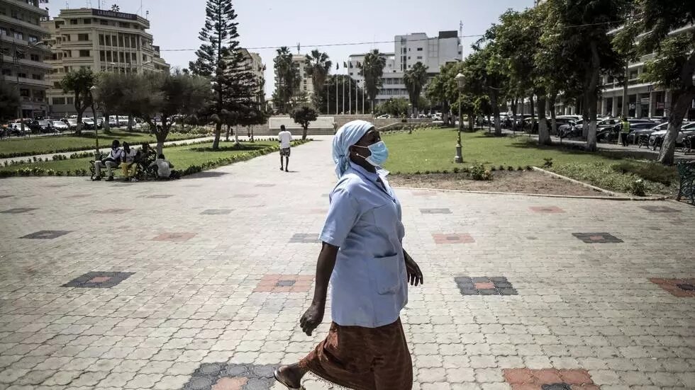 Une dame porte un masque contre le coronavirus passe à la place de l'indépendance