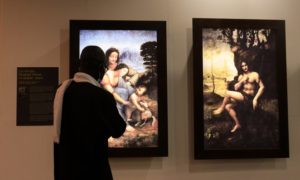 Un homme inspecte des tableaux de Léonard de Vinci lors de l'exposition