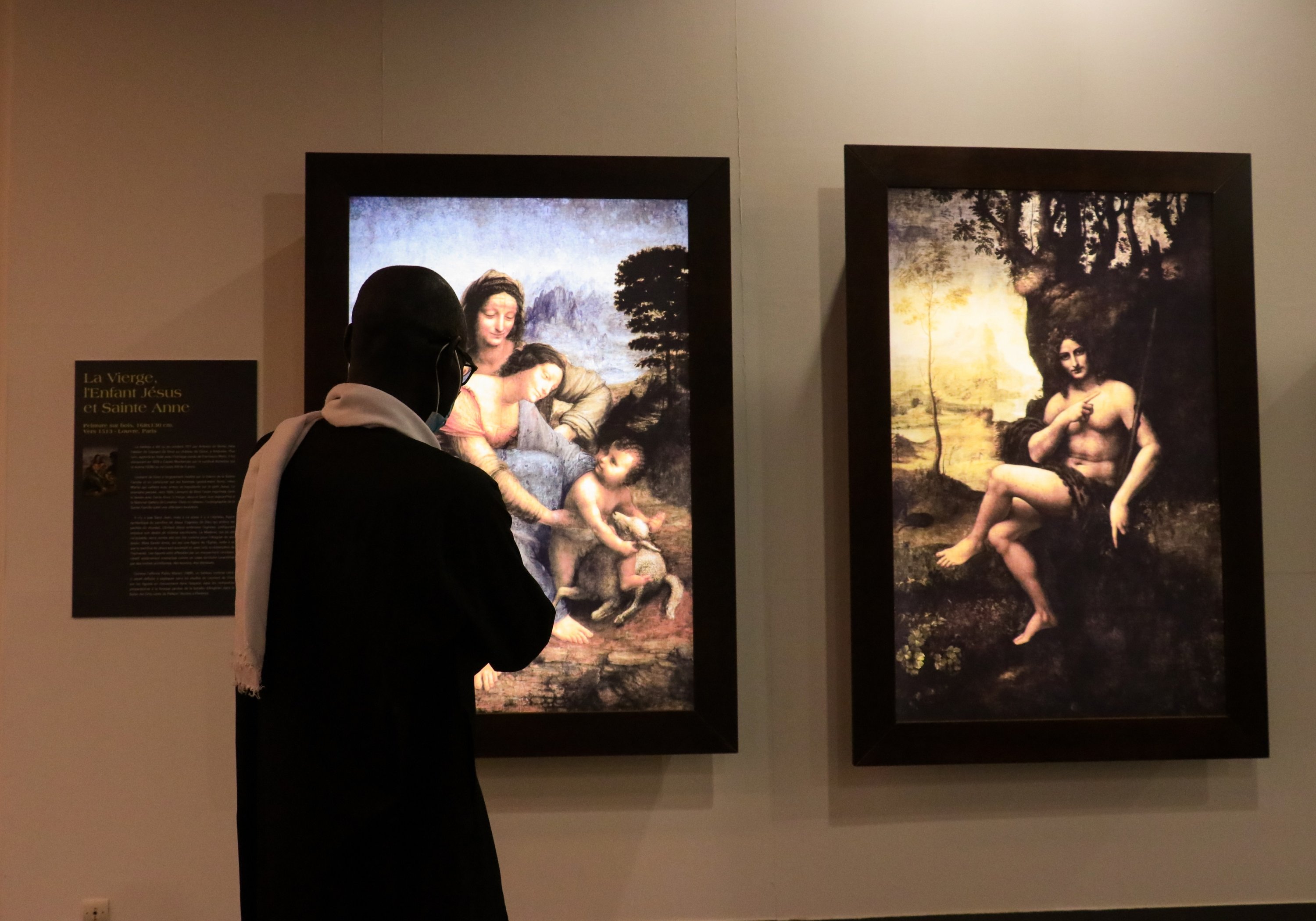 Un homme inspecte des tableaux de Léonard de Vinci lors de l'exposition