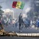 Un jeune manifeste en soulevant le drapeau du Sénégal