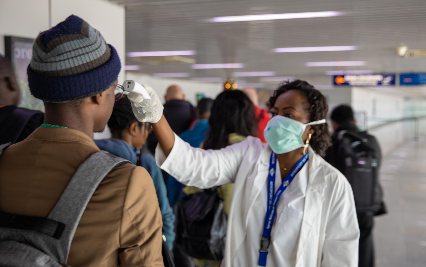 Un agent de santé prend la température d'un homme à l'aéroport