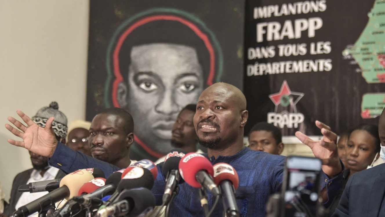 Un portrait d’Omar Blondin Diop est affiché derrière le militant sénégalais Guy Marius Sagna au siège du Front pour une révolution anti-impérialiste populaire et panafricaine (Frapp), à Dakar, le 25 mars 2021. SEYLLOU / AFP