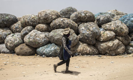 Une femme passe devant des déchets recyclables dans la décharge de Mbeubeuss