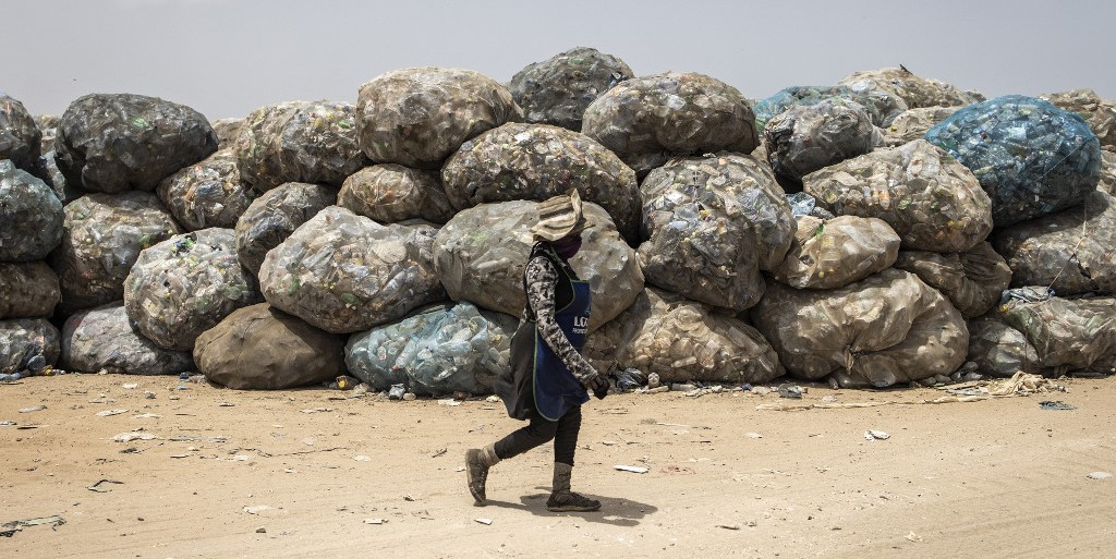 Une femme passe devant des déchets recyclables dans la décharge de Mbeubeuss