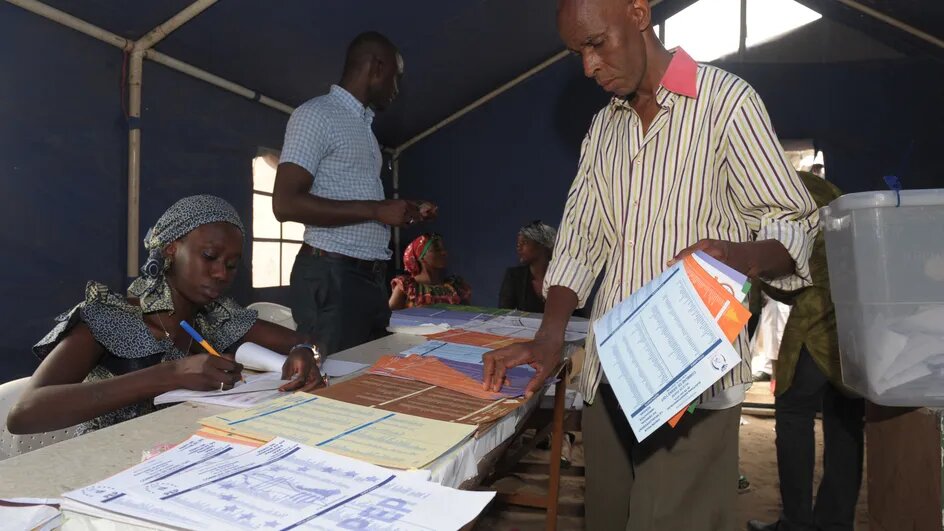 Un homme choisit des bulletins pour voter aux élections municipales et départementales du 29 juin 2014 dans un bureau de vote à Dakar, la capitale du Sénégal.